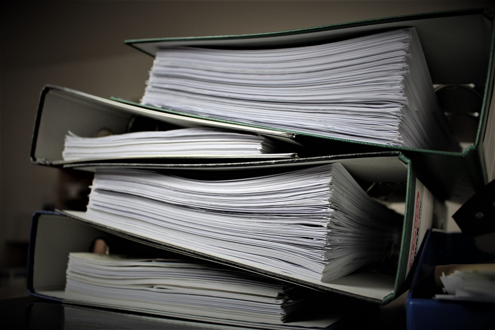 Gros plan sur des classeurs empilés remplis de documents pour un usage de bureau ou éducatif.